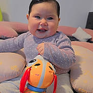 Arleth is registered to the contest to win money with this photo: baby, child, smiling, toy, colorful_toy, indoor, cushion, happy, face, person, sitting, clothing, pants, long_sleeve, cute, playful, infant, home, fun, bright