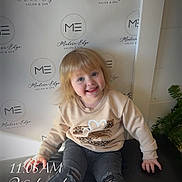 Eliana joined the competition — help win amazing prizes! child, smiling, blonde_hair, sitting, jeans, sneakers, sweatshirt, indoor, logo_background, modern_edge, cushion, happy, portrait, casual, fashion, young_child, event, photography, time_overlay, day_overlay