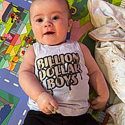 Andrew joined the competition — help win amazing prizes! baby, child, infant, play_mat, colorful, shirt, text_on_clothing, black_shorts, blanket, cartoon, road_pattern, toy_area, cute, smiling, lying_down, indoors, person, young_child, happy, playtime