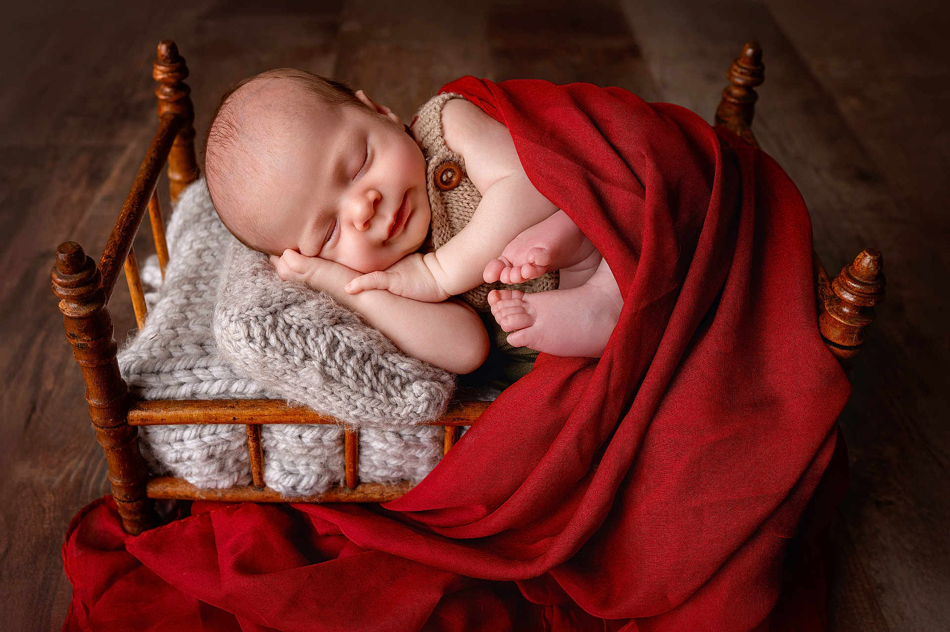 Aron a rejoint le concours — aidez-le/la à gagner de superbes lots ! baby, newborn, infant, sleeping, wooden_bed, knitted_blanket, red_blanket, cozy, toes, hand, portrait, studio_photography, rustic, wood_floor, button, swaddle, peaceful, blanket, child, cute