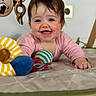 baby, infant, smiling, play_mat, toy, soft_toy, colorful, child, indoors, happy, cute, face, hand, clothing, pink_shirt, crawling, expression, closeup, portrait, floor