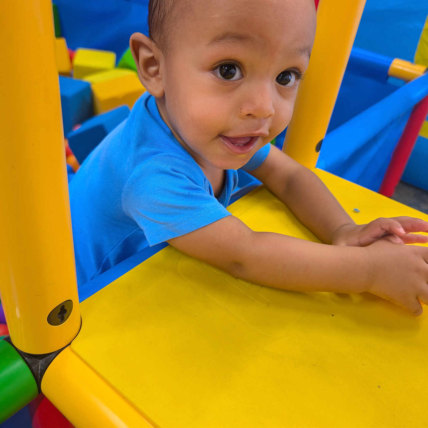 Kordell is registered to the contest to win money with this photo: child, toddler, baby, face, smiling, happy, playground, indoor, play_structure, yellow, blue, colorful, ball_pit, plastic, portrait, arms, hands, eyes, playtime, joy