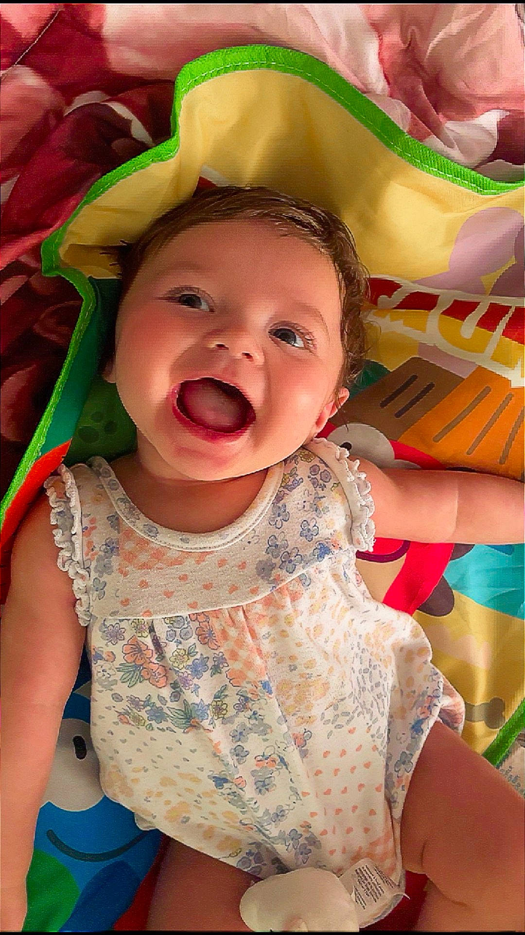 Whitley Jean is registered to the contest to win money with this photo: baby, blanket, cheek, child, closeup, colorful, eyes, floral_dress, hair, happy, indoors, infant, lying_down, open_mouth, play_mat, portrait, skin, sleeveless, smiling, toy