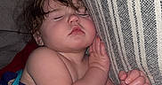 Whitley is registered to the contest to win money with this photo: baby, sleeping, child, infant, portrait, indoors, bed, bedding, curtain, striped_fabric, cozy, nap, relaxed, face, hands, curly_hair, blanket, home, close_up, cuddling