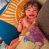 Whitley is registered to the contest to win money with this photo: baby, infant, smiling, happy, portrait, face, curly_hair, wet_hair, lying_down, couch, pillows, blanket, colorful, indoors, home, relaxed, diaper, child, cozy, photography