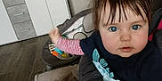 Maël a rejoint le concours — aidez-le/la à gagner de superbes lots ! baby, child, blue_eyes, dinosaur_shirt, striped_sleeves, tousled_hair, hand, adult, indoor, cabinet, wooden_floor, framed_pictures, cozy_room, person, sitting, curious, holding, furniture, portrait, casual_clothing