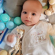 Malo a rejoint le concours — aidez-le/la à gagner de superbes lots ! baby, infant, toy, giraffe_teether, play_mat, balls, stuffed_animal, onesie, child, cute, face, hand, lying_down, soft_toys, indoor, colorful, expression, clothing, head, young