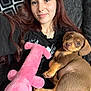 woman, puppy, dog, plush_toy, couch, black_shirt, brown_hair, indoor, pet, smile, face, young_adult, relaxing, holding, soft_toy, cute, comfort, closeup, casual, resting