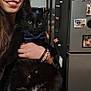woman, cat, black_cat, bow_tie, smile, indoor, kitchen, fridge, magnet, note, bracelet, long_hair, holding, pet, portrait, human, accessory, happy, face, furniture