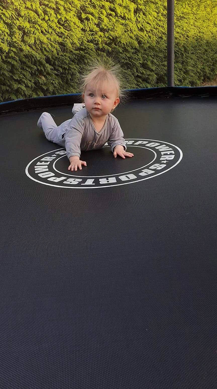 Talya a rejoint le concours — aidez-le/la à gagner de superbes lots ! asphalt, automotive_wheel_system, baby, baby_toddler_clothing, child, circle, floor, flooring, fun, grass, grey, leisure, person, plant, play, recreation, road_surface, sitting, toddler, trampolining_equipment_and_supplies