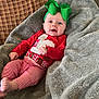 Lainey joined the competition — help win amazing prizes! baby, infant, green_bow, red_clothing, striped_pants, blanket, plaid_couch, smiling, happy, indoors, cozy, child, portrait, festive, holiday, cute, headband, sitting, soft_texture, person