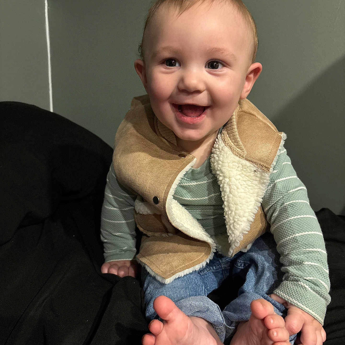 Liam joined the competition — help win amazing prizes! baby, child, clothing, cozy, cute, face, feet, fingers, happy, head, indoor, jeans, long_sleeve, person, sitting, skin, smiling, striped, toes, vest
