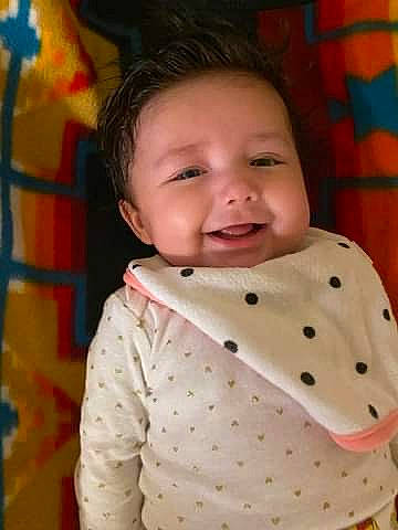 Loretta is registered to the contest to win money with this photo: baby, baby_products, baby_toddler_clothing, cheek, child, collar, face, fun, happy, head, leisure, linens, nose, pattern, person, play, skin, sleeve, smile, textile