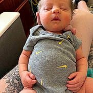 Grayson joined the competition — help win amazing prizes! baby, sleeping, onesie, tattoo, arm, hand, fingers, hair, indoor, furniture, couch, person, clothing, skin, legs, footwear, pacifier, relaxation, casual, closeup
