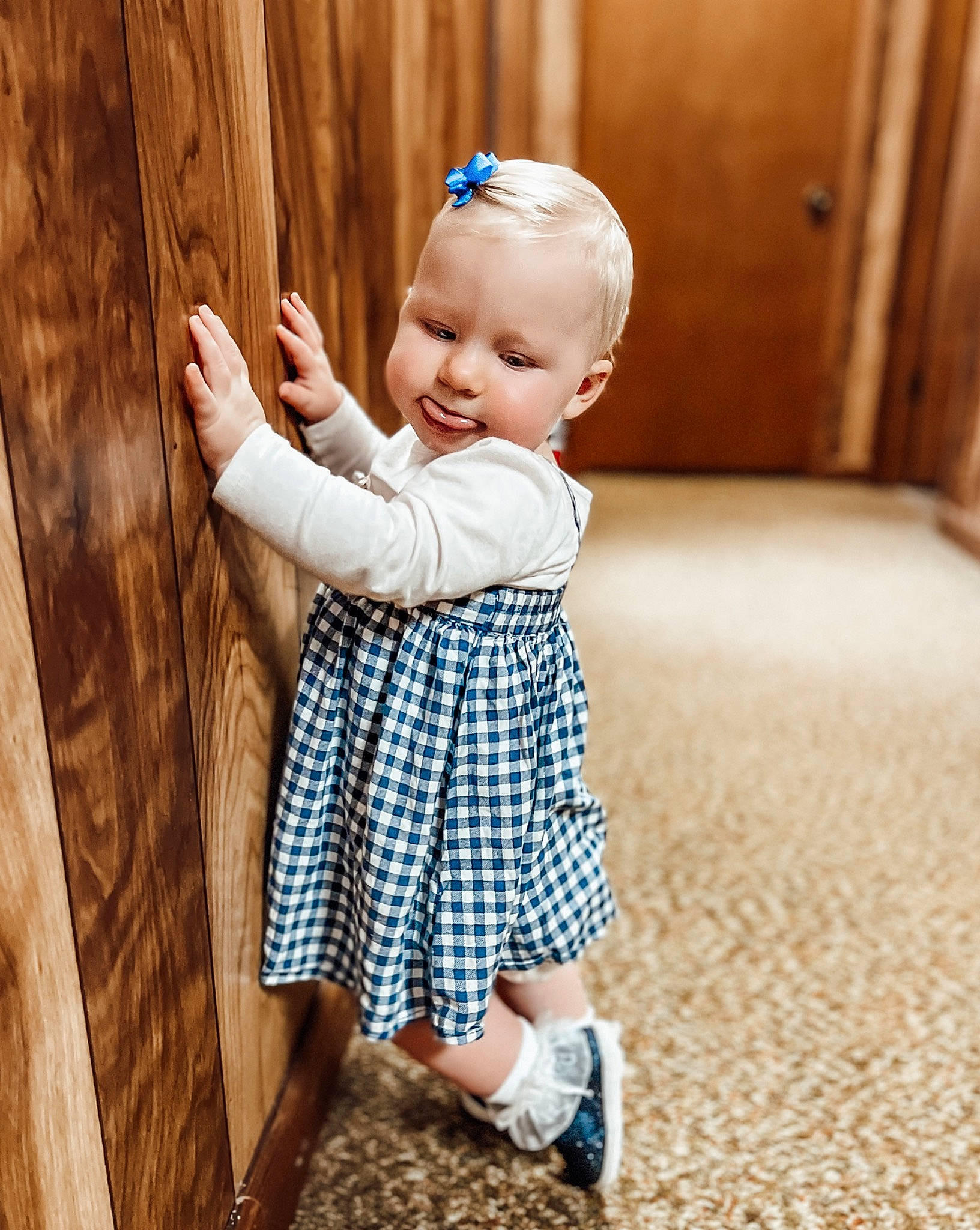 Lucy is registered to the contest to win money with this photo: baby, baby_toddler_clothing, child, day_dress, door, eye, face, flooring, foot, happy, head, human_leg, pattern, people_in_nature, person, sitting, sleeve, sock, standing, toddler