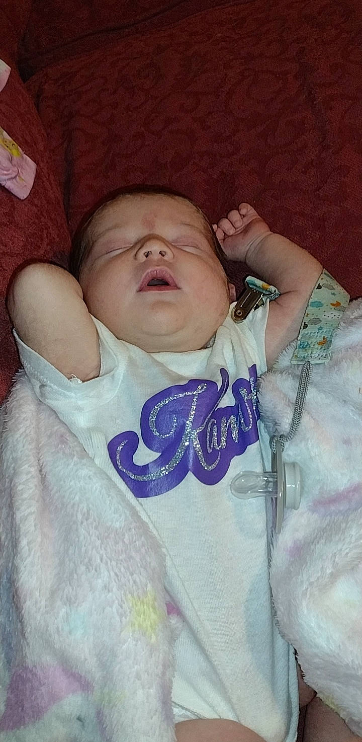 Kamryn is registered to the contest to win money with this photo: baby, baby_toddler_clothing, bedtime, cheek, child, comfort, eye, eyebrow, face, head, iris, linens, lip, mouth, person, room, skin, sleeve, textile, thumb