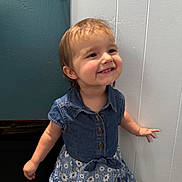 Isabella joined the competition — help win amazing prizes! blue_dress, buttoned_shirt, carpet, child, cute, denim, door, dress, face, floral_pattern, happy, indoor, person, portrait, short_hair, smiling, standing, toddler, wall, young_child