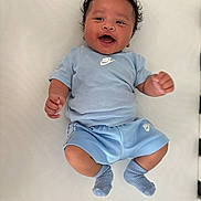 Kamari joined the competition — help win amazing prizes! baby, infant, smiling, blue_clothing, nike_logo, shorts, tshirt, socks, curly_hair, lying_down, happy, cute, child, portrait, indoor, light_background, small_person, baby_boy, casual_wear, soft_surface
