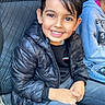 Richard participe au concours pour gagner de l'argent avec cette photo : child, boy, smiling, black_jacket, jeans, car_seat, happy, portrait, indoor, casual_clothing, person, cute, young, sitting, hair, face, warm_clothing, eyes, hands, seat