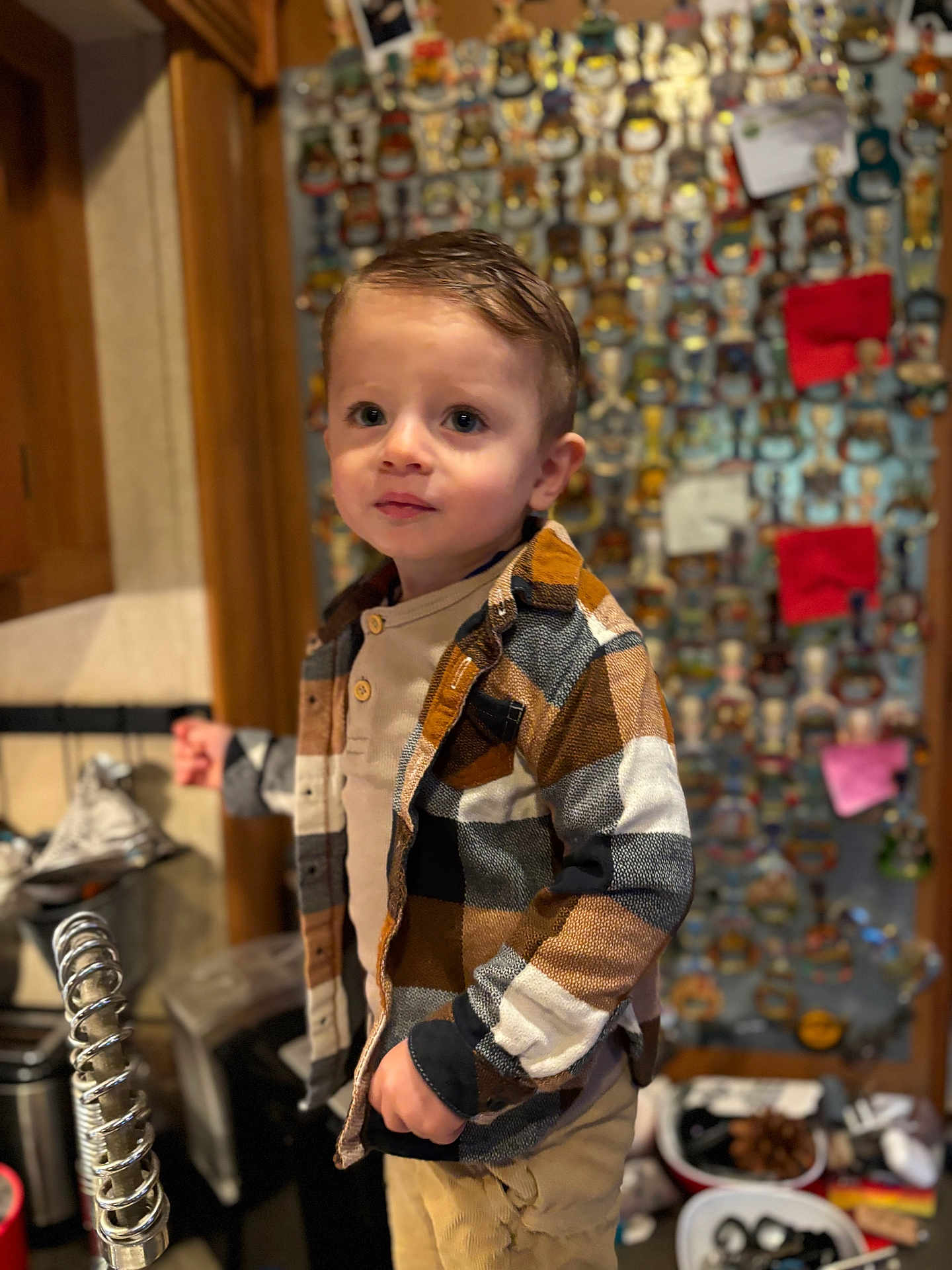 Wilson a rejoint le concours — aidez-le/la à gagner de superbes lots ! child, boy, plaid_shirt, tan_pants, indoor, kitchen, bottle_openers, collection, wall, curly_hair, standing, portrait, furniture, cabinet, countertop, decor, person, casual_clothing, curious, young