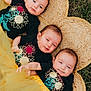 baby, infant, tutu, yellow_skirt, black_shirt, flower_print, woven_mat, grass, outdoor, three_children, lying_down, cute, smiling, head, face, person, toddler, matching_clothes, nature, playful