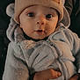 baby, infant, hat, beanie, bear_ears, fuzzy_clothing, hand, ring, closeup, portrait, cute, warm_lighting, eyes, face, child, winter_clothing, person, holding, expression, soft_texture