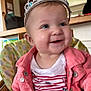 baby, child, tiara, smile, high_chair, jacket, pink_jacket, striped_shirt, indoor, face, cute, happy, infant, person, headwear, cheerful, seated, clothing, portrait, young_child