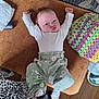 baby, infant, child, couch, cushion, crocheted_pillow, toy_car, floor, wooden_floor, clothing, long_sleeve_shirt, pants, daisy_pattern, leopard_print, person, face, arms_up, indoor, expression, sock