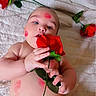 Angelo is registered to the contest to win money with this photo: baby, rose, flower, kiss_marks, blanket, child, skin, hand, face, mouth, red, green, leaf, book, soft_texture, lying_down, cute, infant, holding, nibbling