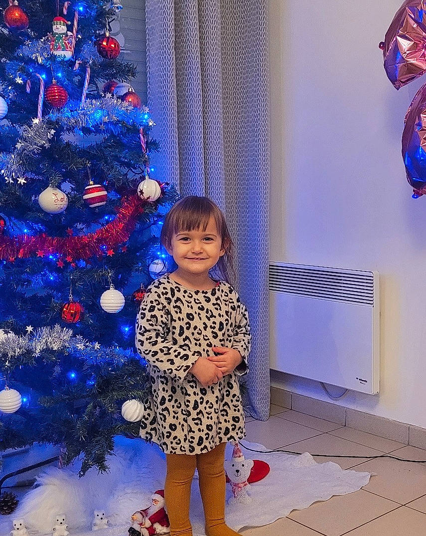 Lola a rejoint le concours — aidez-le/la à gagner de superbes lots ! blue, christmas_ornament, christmas_tree, electric_blue, evergreen, fun, happy, holiday_ornament, human_body, joy, light, ornament, person, photograph, plant, purple, red, smile, standing, toddler