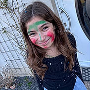 Eléa a rejoint le concours — aidez-le/la à gagner de superbes lots ! black_shirt, casual_clothing, celebration, child, confetti, door, face_paint, fun, girl, happy, long_hair, nature, necklace, outdoor, plants, portrait, rocks, smiling, wall, young