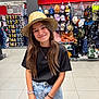 accessories, black_tshirt, bracelet, casual_clothing, child, denim_skirt, fashion, girl, happy, hat, hats, indoor, long_hair, portrait, retail, shopping, smile, store, straw_hat, young