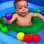 Jayden is registered to the contest to win money with this photo: toddler, child, pool, inflatable, water, ball, colorful, green_ring, purple_ball, yellow_ball, red_ball, blue_pool, curly_hair, play, summer, fun, water_toy, skin, baby, outdoor