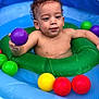 toddler, child, pool, inflatable, water, ball, colorful, green_ring, purple_ball, yellow_ball, red_ball, blue_pool, curly_hair, play, summer, fun, water_toy, skin, baby, outdoor