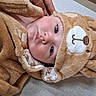 Pj is registered to the contest to win money with this photo: baby, child, face, costume, bear, hood, fuzzy, soft, cute, infant, clothing, hand, portrait, indoors, expression, looking, lying_down, skin, head, eyes