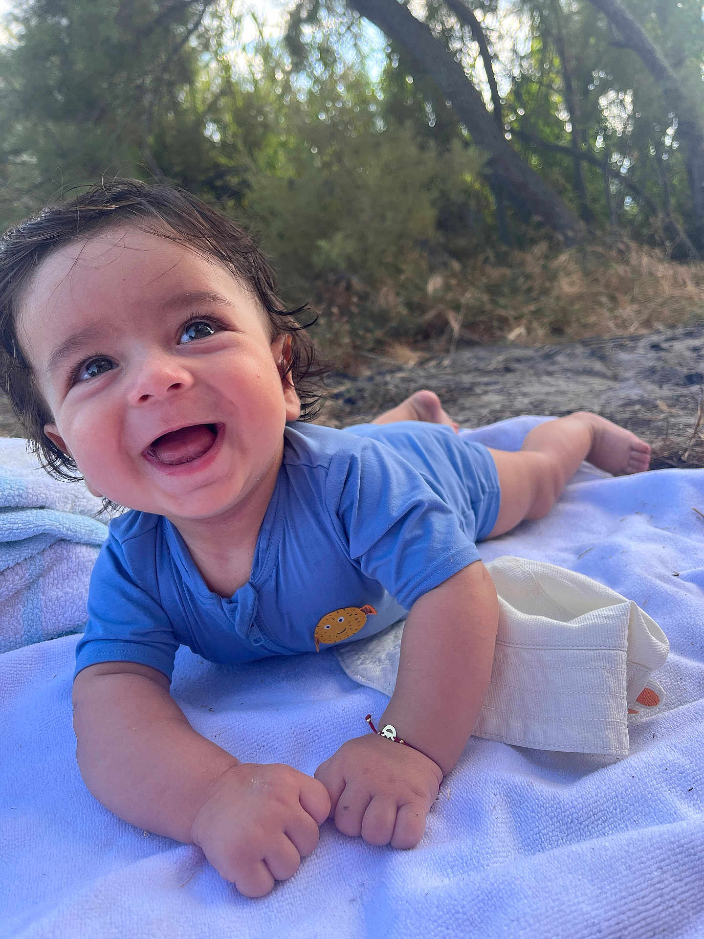 Yanis a rejoint le concours — aidez-le/la à gagner de superbes lots ! baby, smiling, blue_shirt, outdoor, blanket, nature, greenery, happy, toddler, child, portrait, face, cute, sunlight, skin, hand, expression, lying_down, grass, daylight
