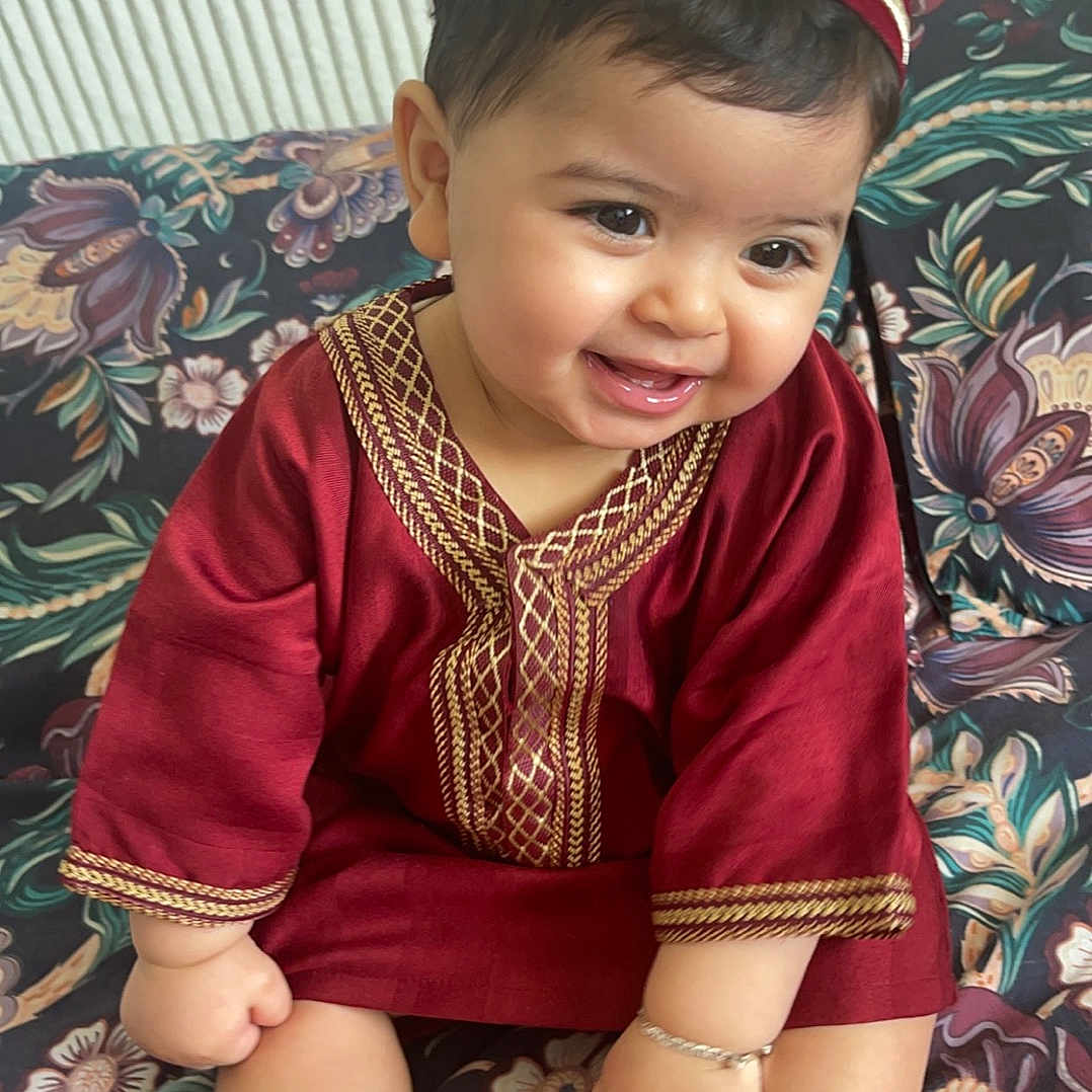 Sultan a rejoint le concours — aidez-le/la à gagner de superbes lots ! baby, barefoot, bracelet, child, couch, cute, decor, face, floral_pattern, foot, hand, happy, hat, indoors, infant, maroon, portrait, sitting, smiling, traditional_clothing