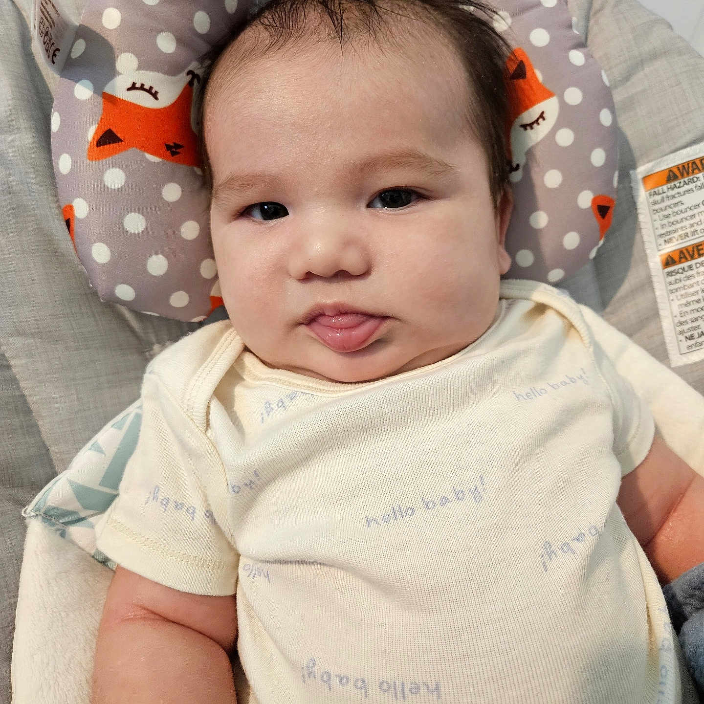 Lloyd joined the competition — help win amazing prizes! baby, infant, child, portrait, face, tongue_out, looking_at_camera, awake, smiling, chubby_cheeks, dark_hair, onesie, clothing, cushion, baby_seat, fox_pattern, polka_dots, indoor, close_up, safety_label