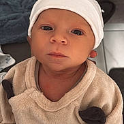 Gabriel participe au concours pour gagner de l'argent avec cette photo : baby, infant, face, hat, clothing, beige, white, person, portrait, looking, indoors, blanket, soft, cute, young, child, headwear, expressionless, newborn, cozy