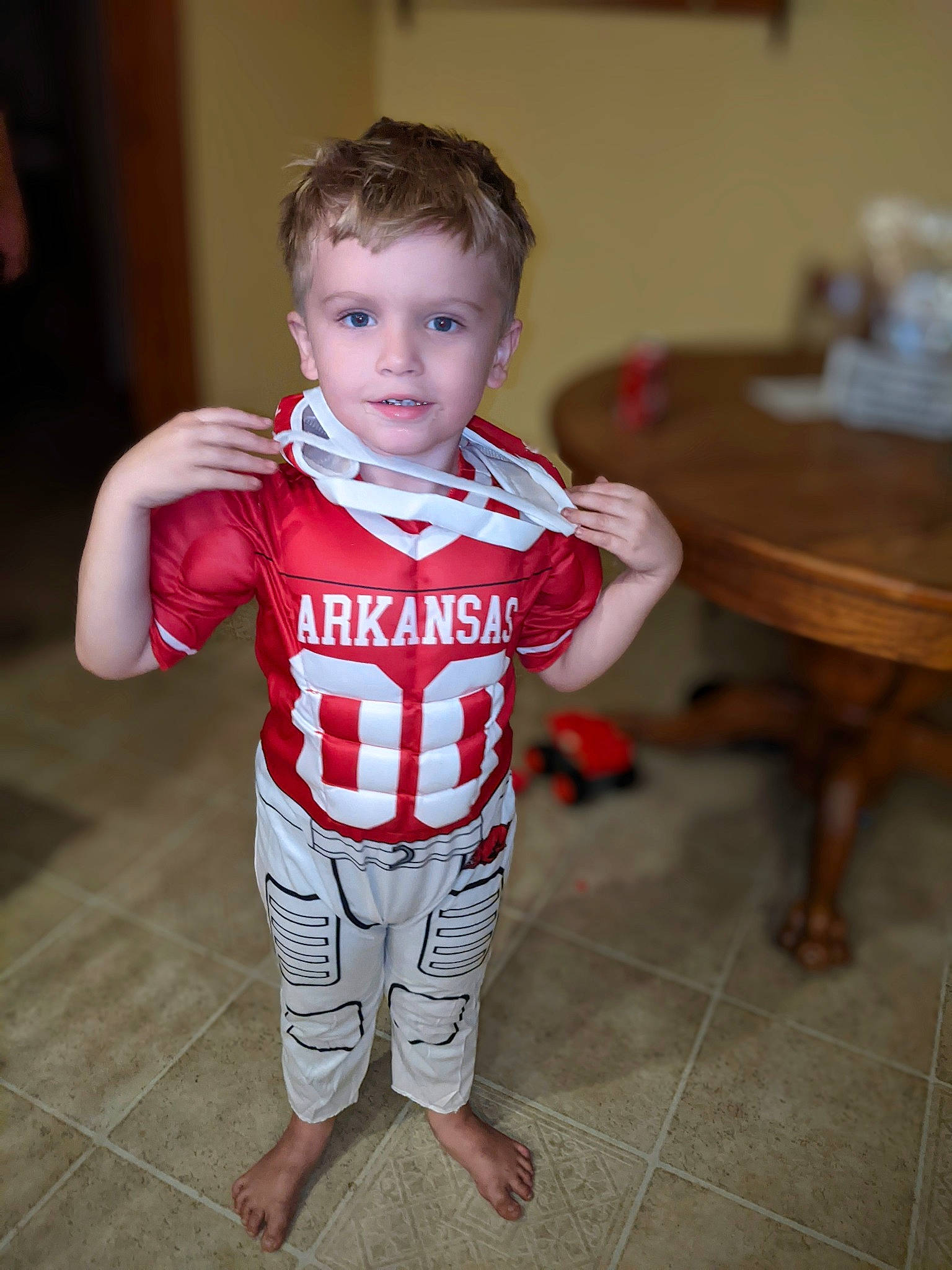 Tommy is registered to the contest to win money with this photo: baby_toddler_clothing, chair, child, event, fashion_design, flash_photography, flooring, fun, happy, human_body, person, room, sitting, sleeve, smile, sportswear, t_shirt, table, toddler, uniform