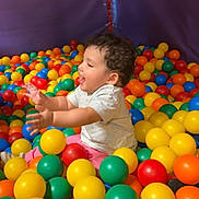 Victoria participe au concours pour gagner de l'argent avec cette photo : ball_pit, casual_clothing, child, colorful_balls, curly_hair, entertainment, fun, happy, indoor, joyful, leisure, pink_pants, play, play_area, recreation, smiling, toddler, vibrant_colors, white_shirt, young_child