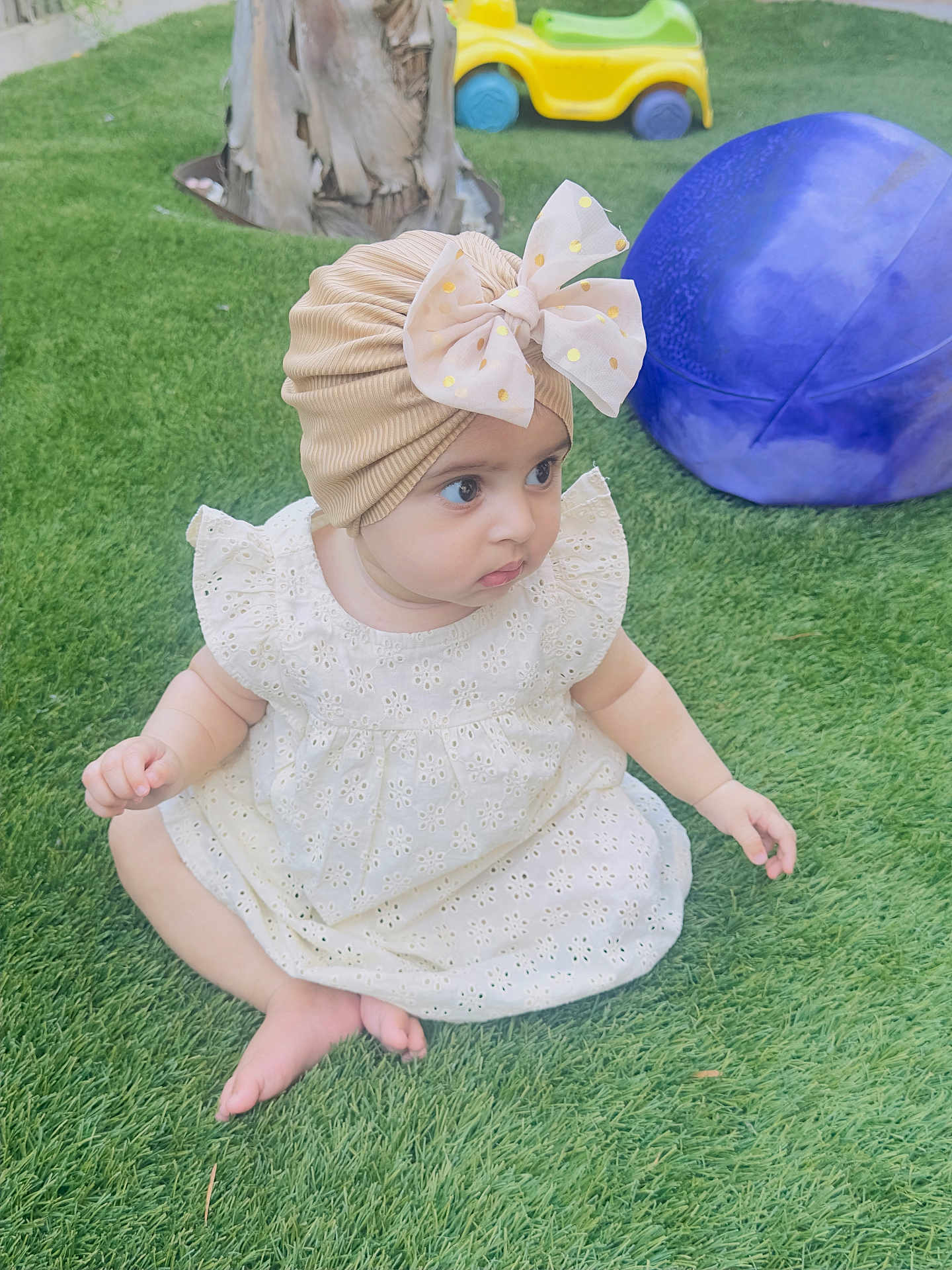 Iman Ali Khan joined the competition — help win amazing prizes! baby, child, grass, outdoor, dress, headwear, turban, bow, playground, toy, purple_ball, yellow_car, curious, sitting, barefoot, greenery, cute, infant, person, daylight