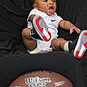 Zaccai joined the competition — help win amazing prizes! baby, child, infant, onesie, white_clothing, black_background, shoes, sneakers, football, nfl, sports, kick, cute, portrait, studio, expression, active, fun, playful, person