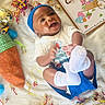 baby, blanket, carrot_bag, celebration, child, clothing, confetti, cute, decorations, easter, festive, happy, headband, holiday, infant, laying_down, sign, smiling, sock, toy