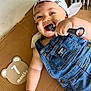 baby, child, denim_overalls, bandana, face_paint, cardboard, tools, wrench, happy, smiling, laying_down, cute, infant, metallic, playful, indoors, hand, portrait, one_month, overalls
