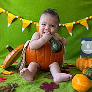 Lucas is registered to the contest to win money with this photo: baby, pumpkin, gourd, green_background, autumn, fall_leaves, smiling, sitting, six_months, milestone, decorations, cute, child, playful, orange, holiday, festive, portrait, indoor, celebration