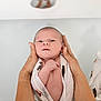 Basile participe au concours pour gagner de l'argent avec cette photo : baby, infant, swaddled, hands, bath, water, newborn, skin, expression, person, adult_hands, cloth, patterned_cloth, floating, calm, gentle, closeup, portrait, white_background, parent