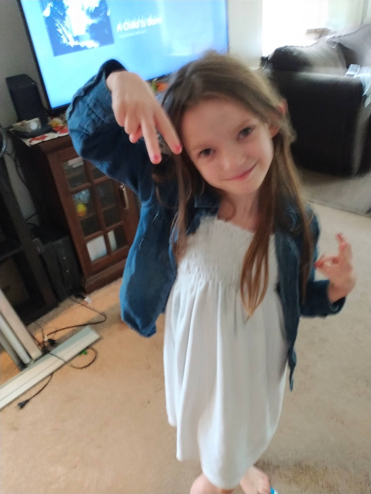 Emily is registered to the contest to win money with this photo: child, fashion_design, finger, floor, flooring, fun, gesture, hair, hand, happy, joint, joy, long_hair, person, shoulder, skin, sleeve, smile, standing, thumb