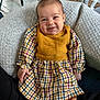 baby, casual, chair, child, comfortable, cozy, cushion, dress, face, floor, happy, home, indoor, knit_vest, person, plaid, seated, smile, table, wood_floor