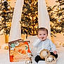 Jadiel is registered to the contest to win money with this photo: baby, book, celebration, child, christmas_tree, cute, decorations, festive, gold, happy, holiday, indoors, lights, ornaments, portrait, seasonal, sitting, smiling, white_rug, winter